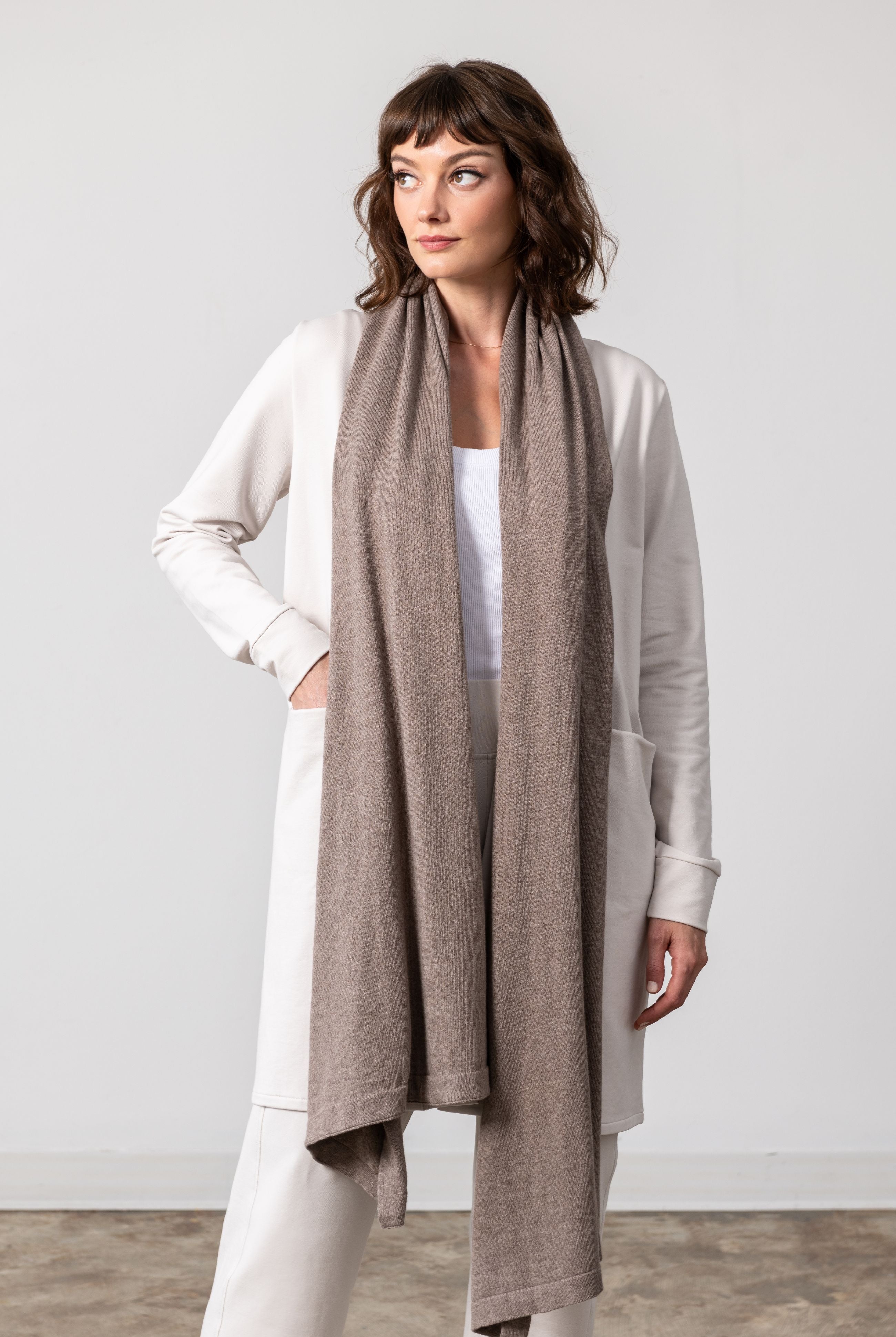 Women shown wearing a dark beige scarf draped around her neck